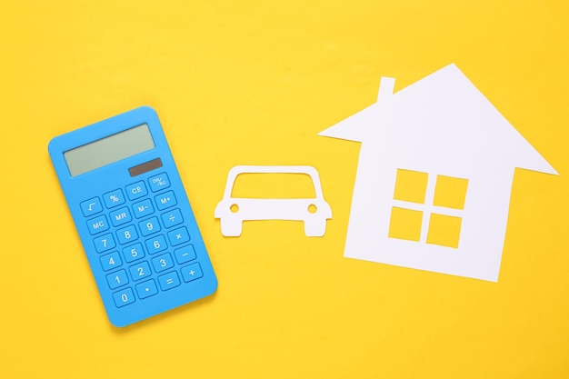 Rechner Papercut Haus und Auto auf gelbem Hintergrund Sachversicherung