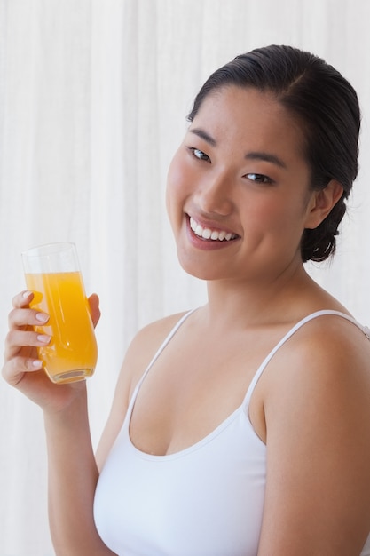 Recht asiatische Frau, die Glas Orangensaft hält