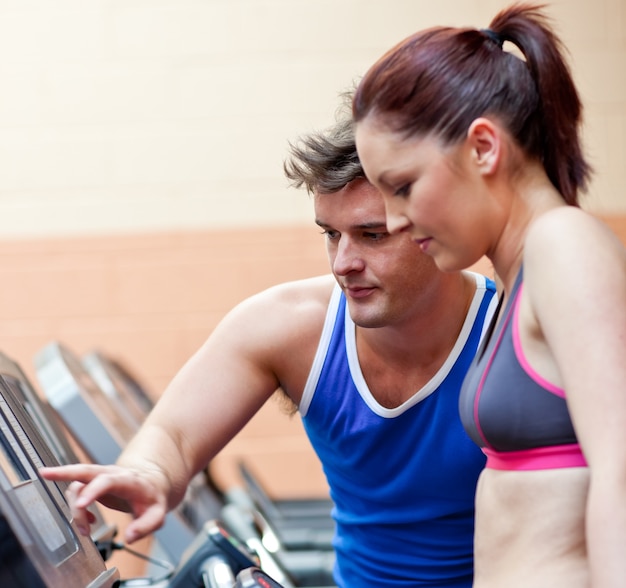 Foto recht athletische frau, die auf einer laufenden maschine mit ihrem persönlichen trainer steht