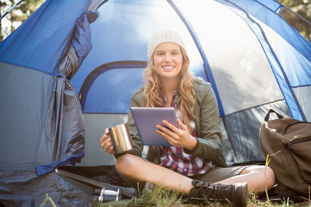 Recht blonder Camper, der Tablette verwendet und Schale hält