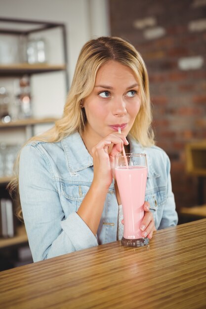 Recht blonder trinkender Smoothie durch Stroh