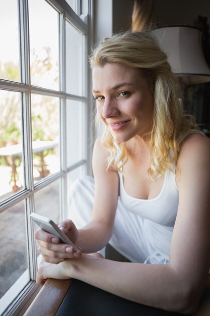 Recht blondes Sitzen am Fenster, das einen Text sendet