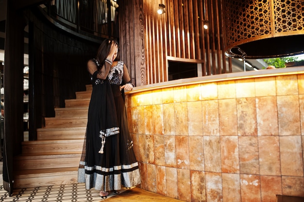 Recht indisches Mädchen im schwarzen Sareekleid warf am Restaurant auf.