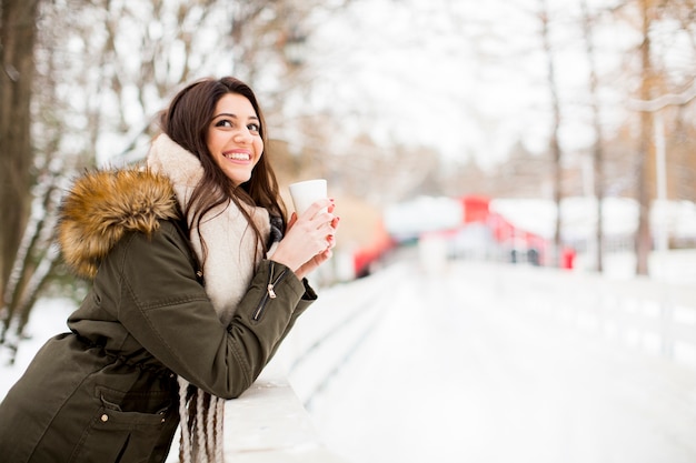 Recht junge Frau, die an einem kalten Wintertag heißen Tee trinkt