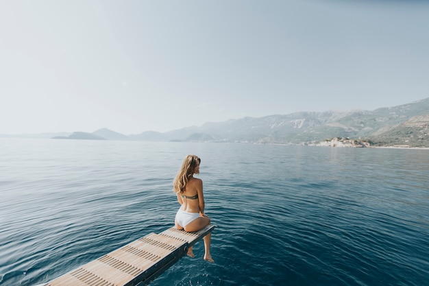 Recht junge Frau, die auf der Yacht auf Meer am sonnigen Tag sich entspannt