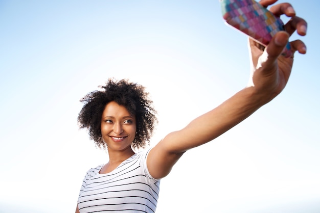 Recht junge Frau, die draußen selfie mit Handy nimmt