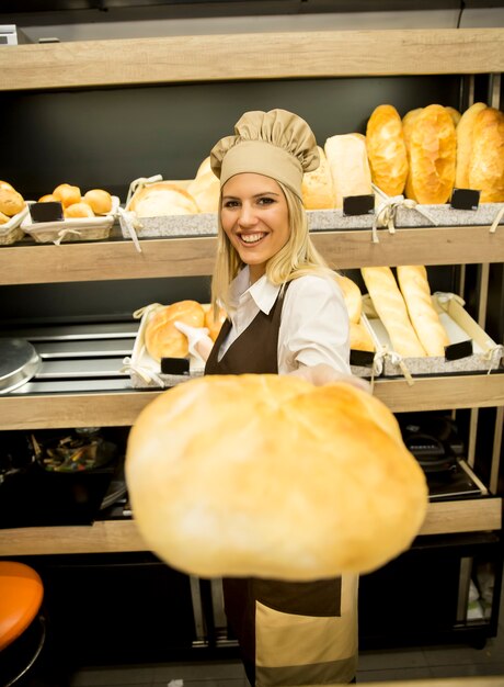 Recht junge Frau, die frisches Brot in der Bäckerei verkauft