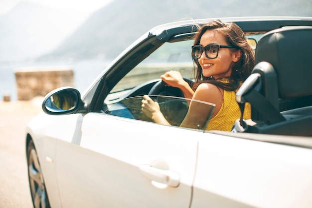 Recht junge Frau im weißen Cabrioletauto