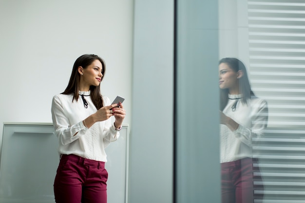 Recht junge Frau mit Handy im Büro