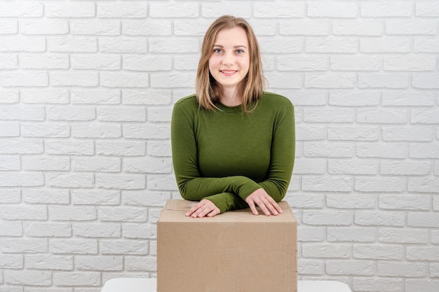 Recht junge Frau mit Paketkasten, der ein Paket liefert