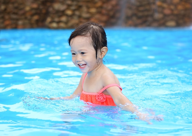 Recht kleines Mädchen, das draußen im Swimmingpool spielt