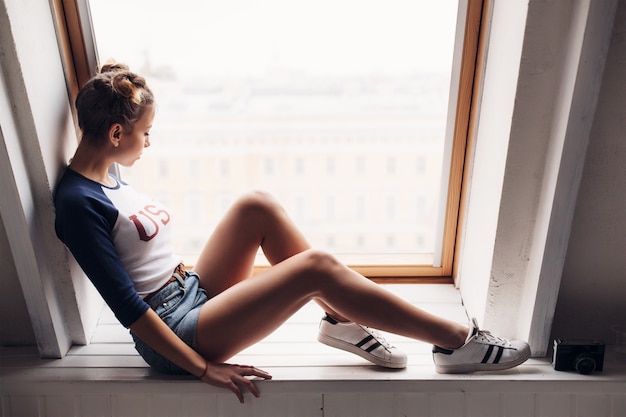 Foto recht sexy gebräunte stilvolle frau, die auf der heißen jungen brunettefrau des fensters aufwirft und sitzt auf fenster im studio aufwirft