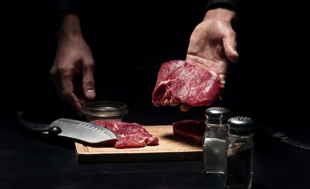 Recibo lindo. perto das mãos do homem segurando a carne depois de cortá-la enquanto cozinha no restaurante.