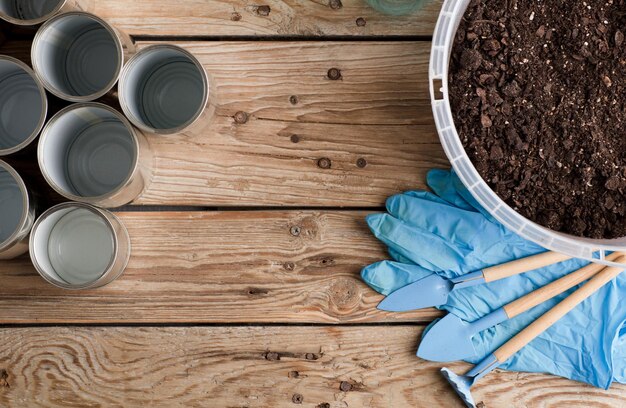 reciclagem criativa em latas de alumínio em casa e recipiente de plástico reciclado com solo no jardim de madeira