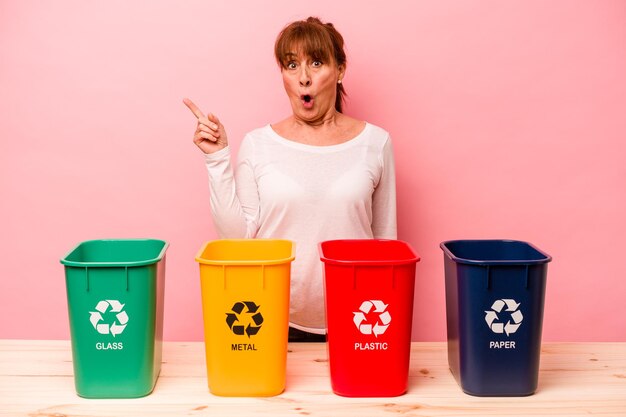 Reciclagem de mulher de meia idade isolada em fundo rosa, apontando para o lado