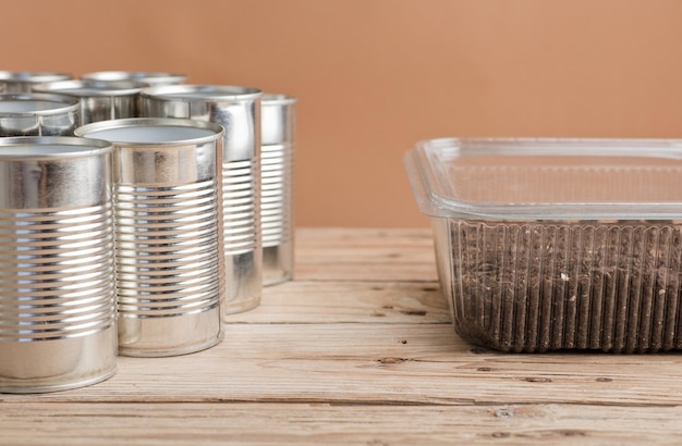 reciclaje creativo en casa latas de aluminio y recipiente de plástico reciclado con tierra en madera de jardín