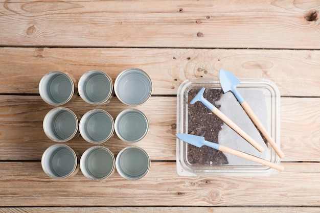 reciclaje creativo en casa latas de aluminio y recipiente de plástico reciclado con tierra en madera de jardín