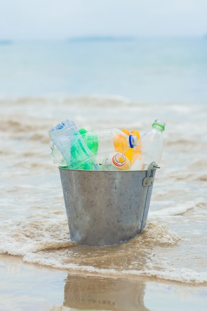 Reciclar, cesta com garrafa de plástico na praia