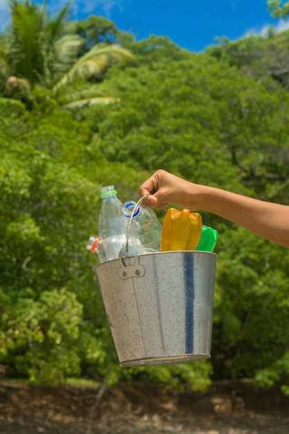 Reciclar, cesta com garrafa de plástico na praia