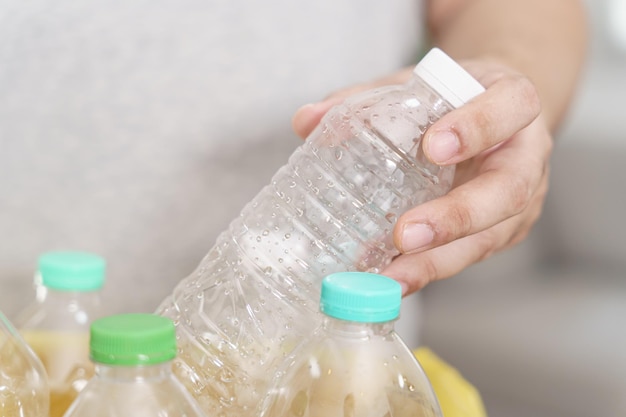 Reciclar em casa conceito eco verde zero Homem jogando garrafa de plástico vazia na lixeira com sacos de lixo amarelos em casa