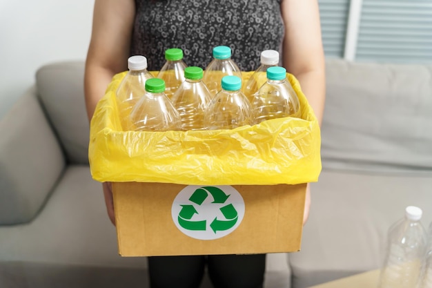 Reciclar em casa conceito eco verde zero Mulher jogando garrafa de plástico vazia na lixeira com sacos de lixo amarelos em casa