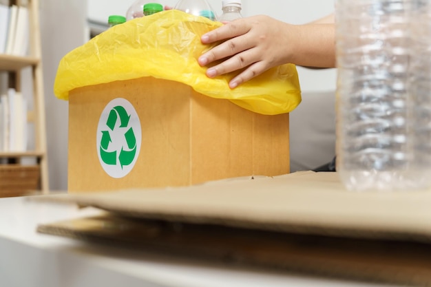 Reciclar em casa conceito eco verde zero Mulher jogando garrafa de plástico vazia na lixeira com sacos de lixo amarelos em casa