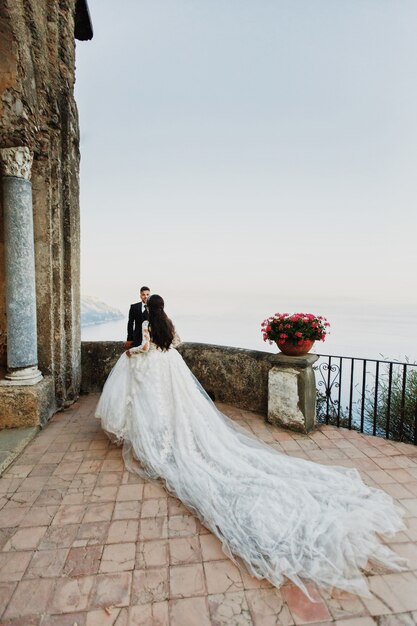 Los recién casados ​​se besan de pie en el balcón sobre el mar