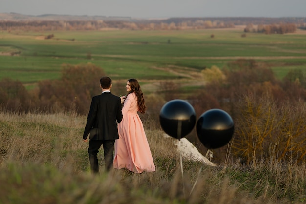 Los recién casados caminan en la naturaleza con grandes globos de helio. concepto de boda