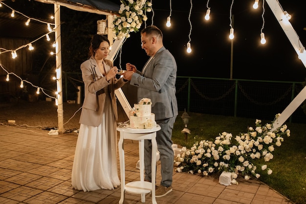 Los recién casados cortan y prueban felizmente el pastel de bodas