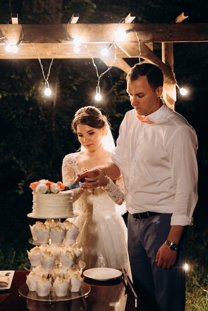 Los recién casados cortan y prueban felizmente el pastel de bodas