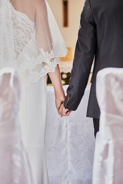 Recién casados se dan la mano durante una boda en una iglesia católica