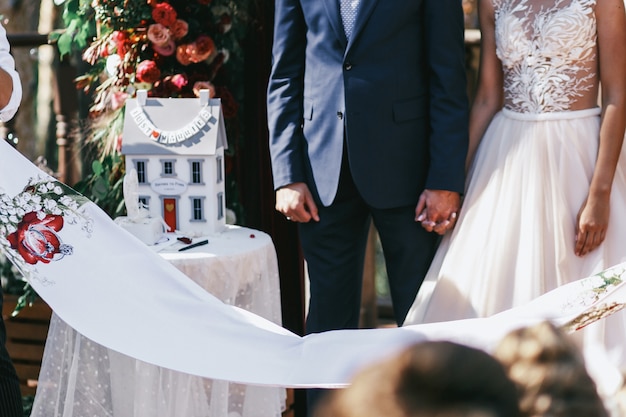 Los recién casados ​​están parados antes de la toalla blanca de la boda