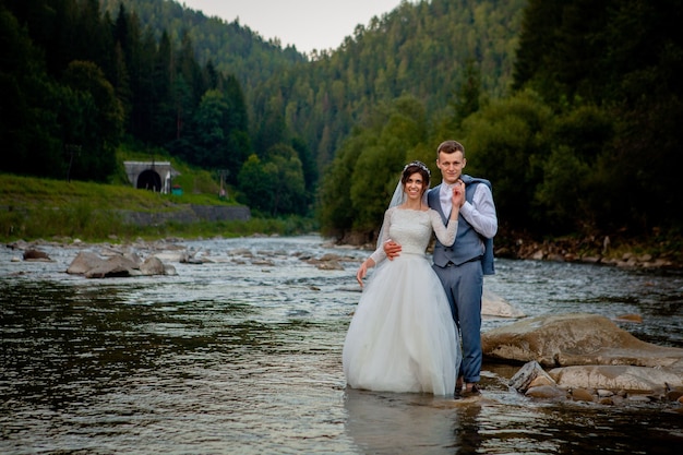 Recién casados felices de pie y sonriendo en el río. Luna de miel, foto para el día de San Valentín.