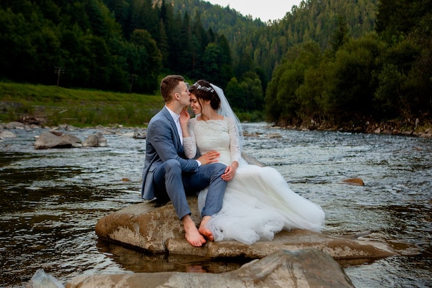 Recién casados felices de pie y sonriendo en el río