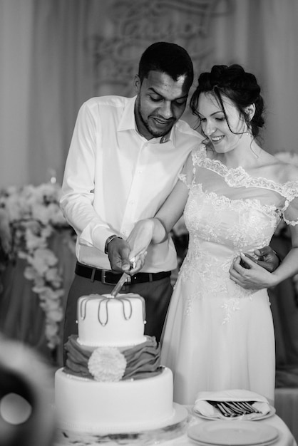 Recién casados felizmente cortan, ríen y prueban el pastel de bodas