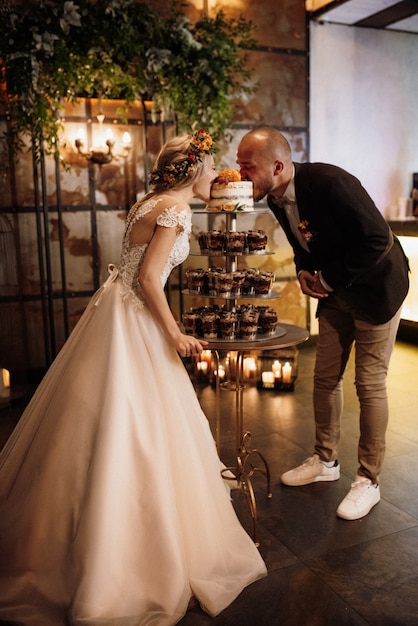 Recién casados felizmente cortan, ríen y prueban el pastel de bodas