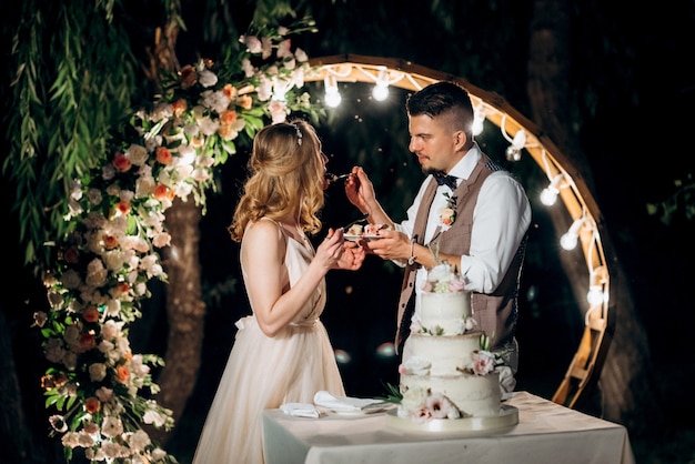 Recién casados felizmente cortan, ríen y prueban el pastel de bodas