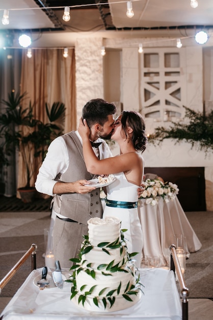 Foto recién casados felizmente cortan, ríen y prueban el pastel de bodas