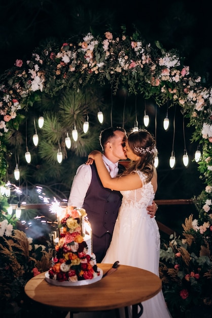 Foto recién casados felizmente cortan, ríen y prueban el pastel de bodas