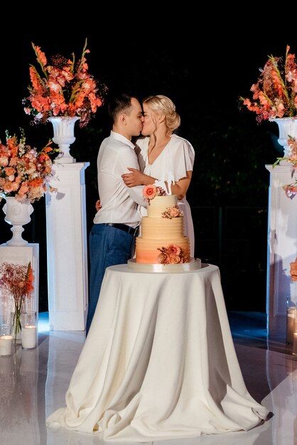 Recién casados felizmente cortan, ríen y prueban el pastel de bodas