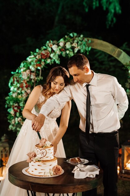 Recién casados felizmente cortan, ríen y prueban el pastel de bodas