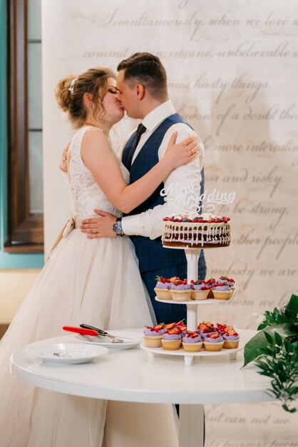 Recién casados felizmente cortan, ríen y prueban el pastel de bodas