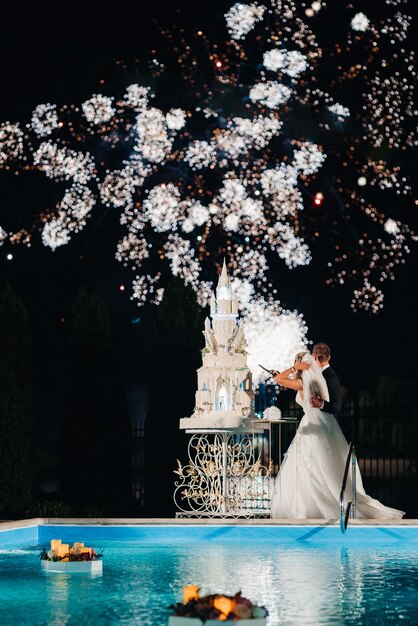 Recién casados felizmente cortan, ríen y prueban el pastel de bodas