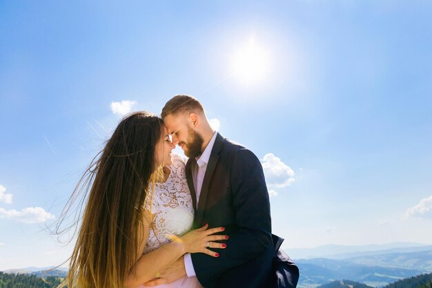 Los recién casados se inclinaron uno contra el otro y sonrieron contra el b