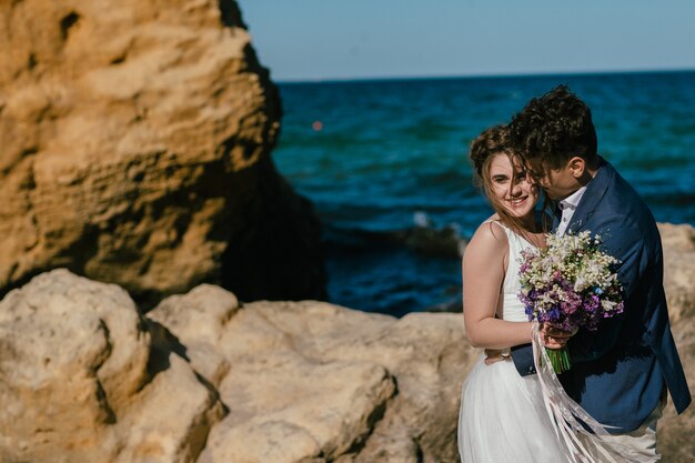 recién casados en la orilla del mar