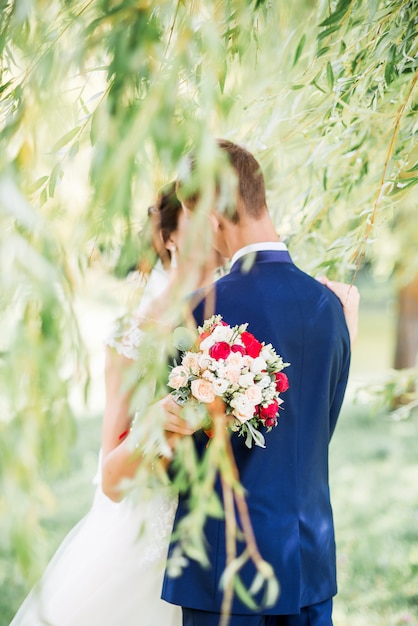 Recién casados en el parque besándose