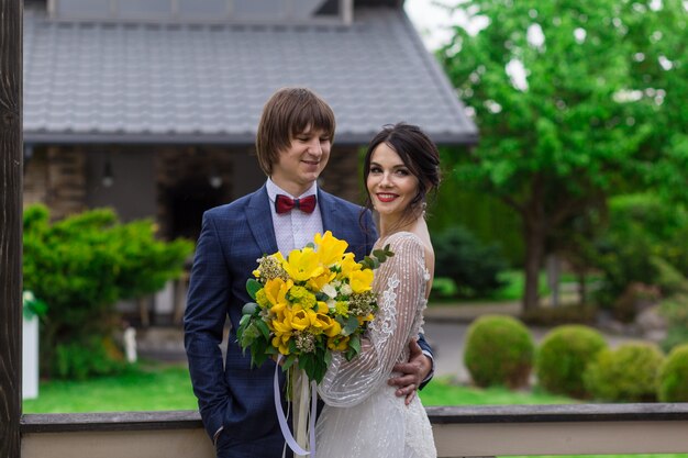 Recién casados posando cerca de la lujosa mansión de madera en la ceremonia de la boda