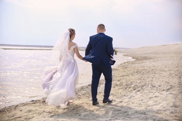 Recién casados posando juntos en la playa