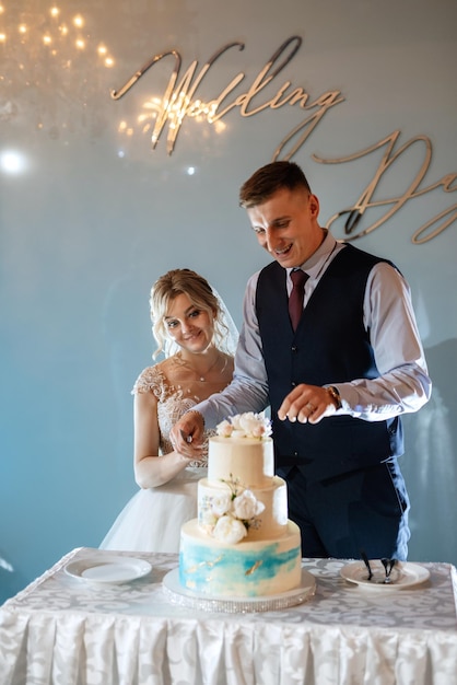 Los recién casados se ríen felizmente y prueban el pastel de bodas