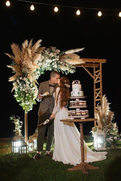 Los recién casados se ríen felizmente y prueban el pastel de bodas